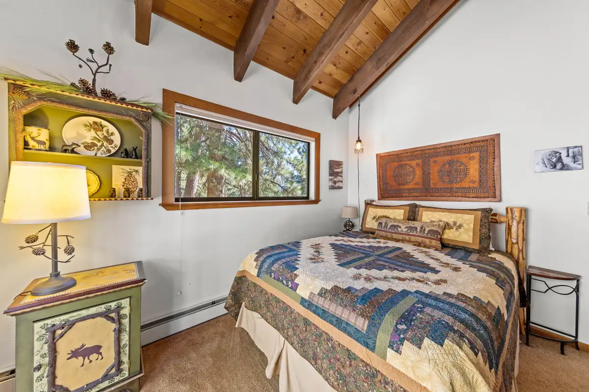 Bedroom with a quilt-covered bed and wood ceiling, Rustic Ridge Retreat