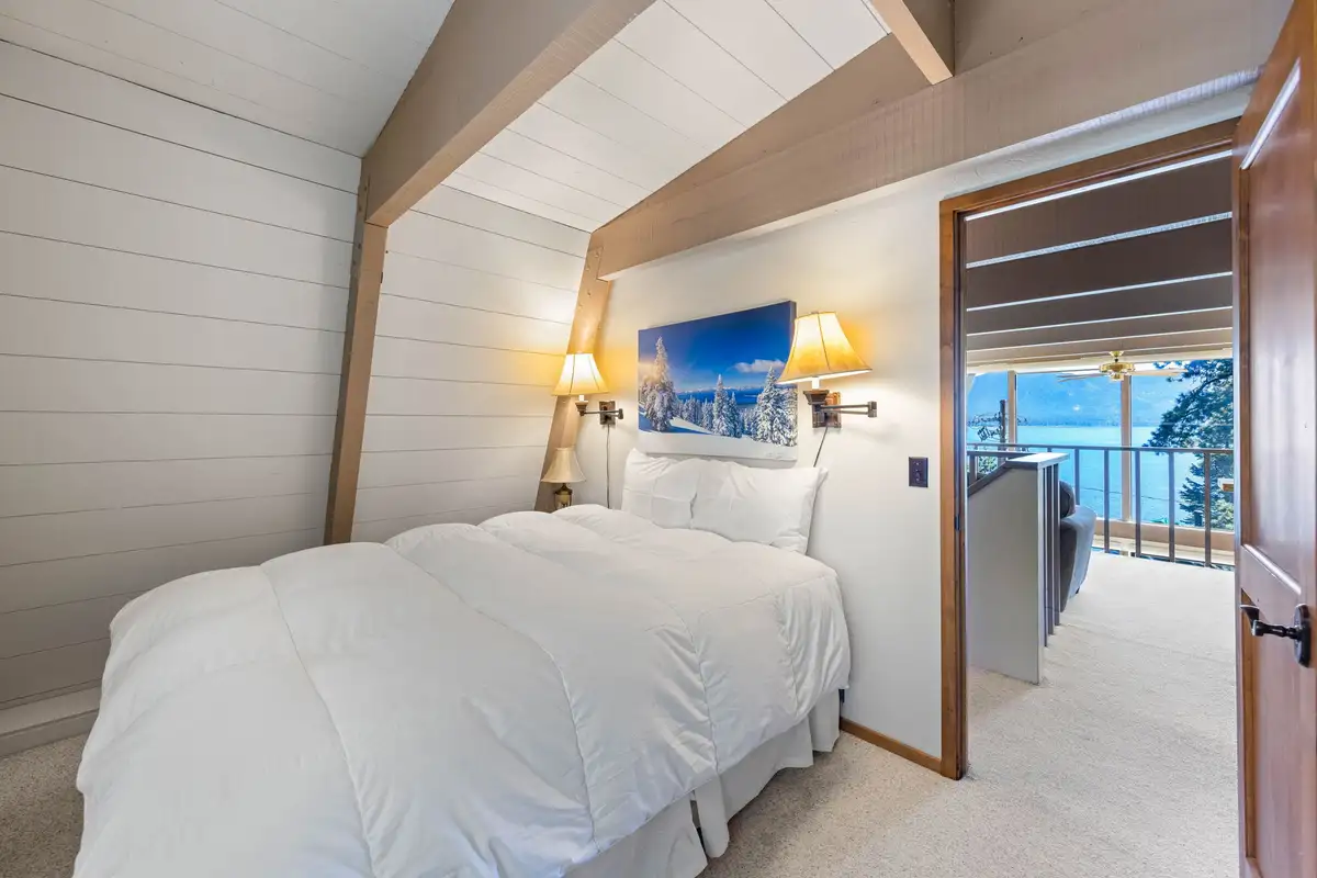 Bedroom with a white bed and doorway to a lake view, Livin' on the Edge