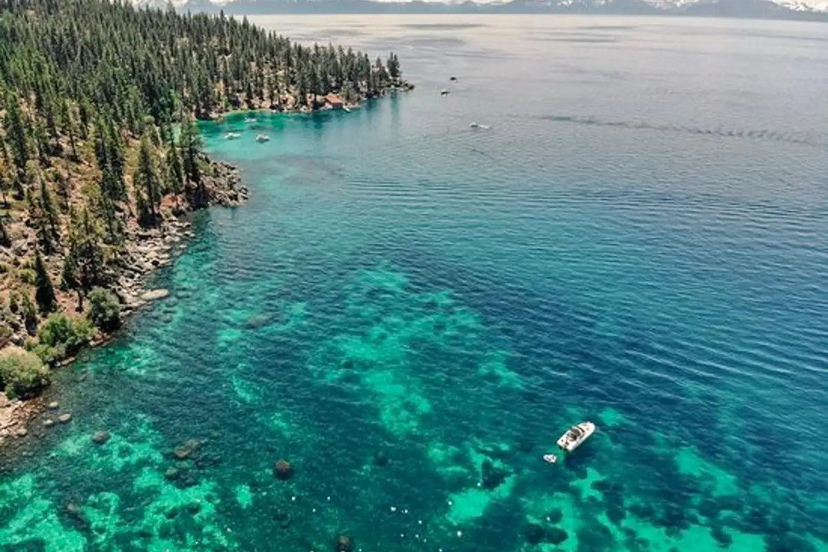 Aerial view of turquoise lake water along a forested shore, Sunlit Incline Retreat