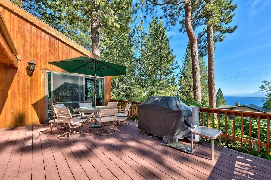 Deck with umbrella table, grill and lake glimpse through pines, Mammoth Haven Retreat