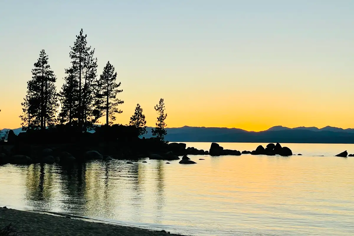 Sunset over a lake with silhouetted pines and rocks, Sunlit Incline Retreat