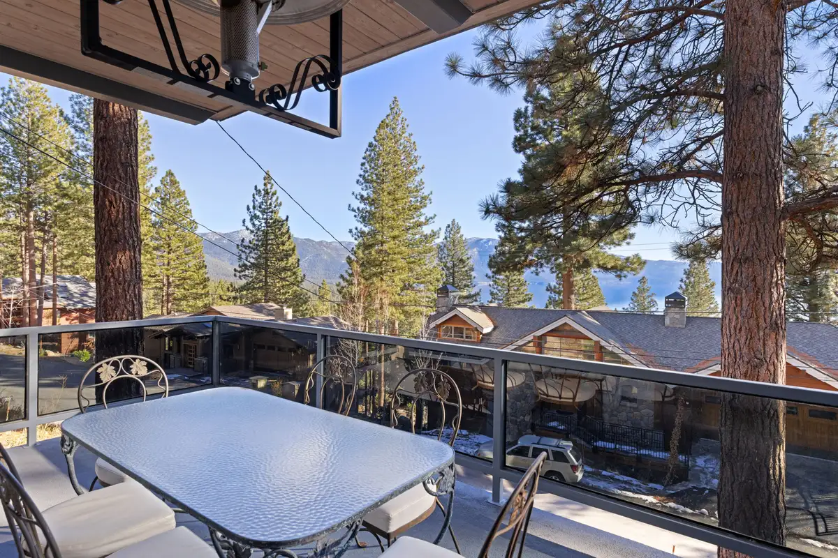 Balcony with dining table and Lake Tahoe visible through pines, 90s Tahoe Time Capsule
