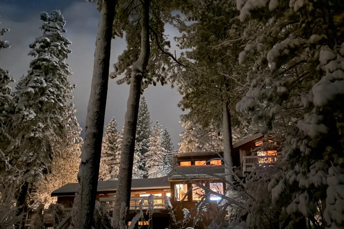 Lit home among snowy pines at dusk, Mammoth Haven Retreat