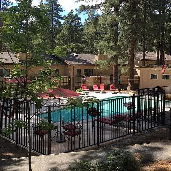Fenced outdoor pool with red lounge chairs, Skiway Suite