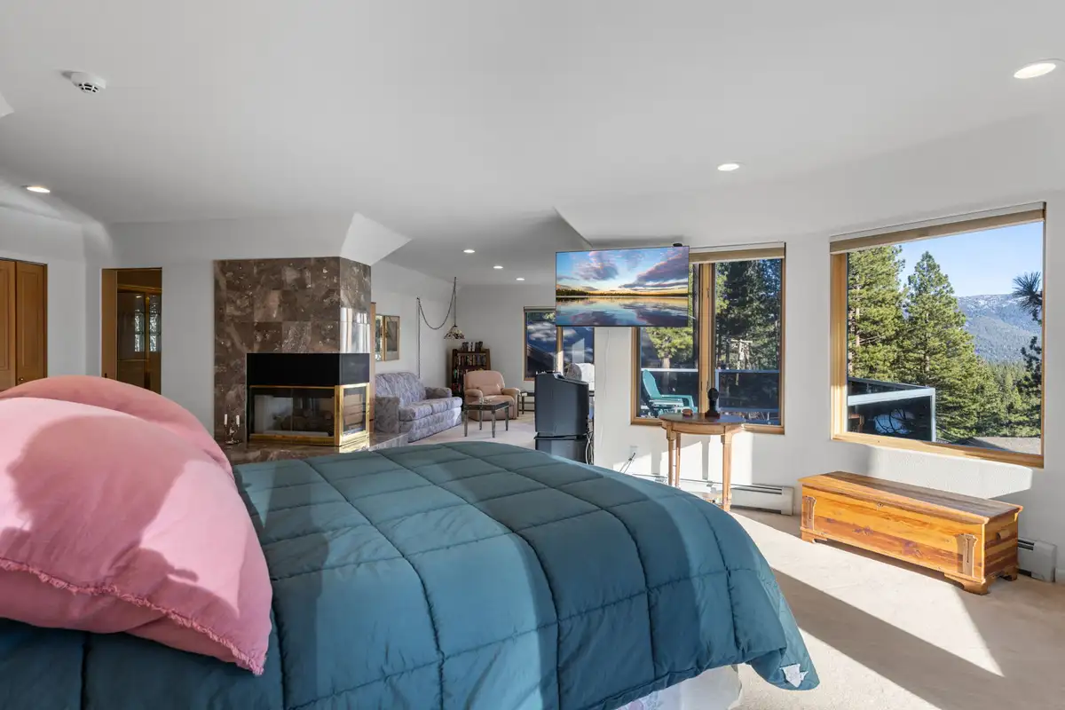 Bedroom with a fireplace and windows overlooking trees, 90s Tahoe Time Capsule