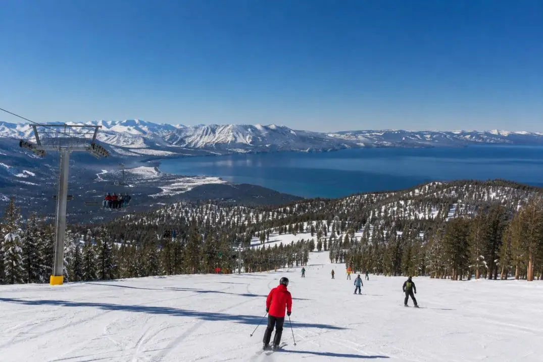 Skiers on a groomed run at Heavenly with Lake Tahoe below